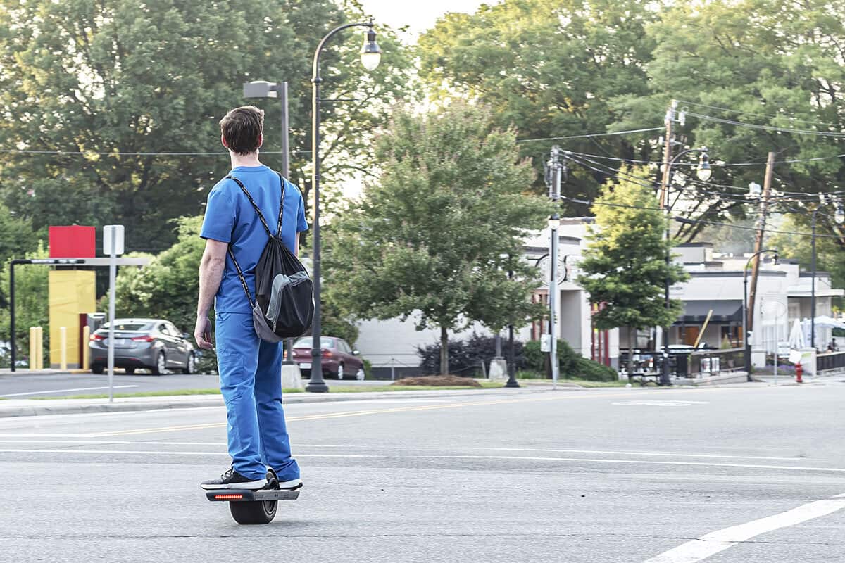 A nurse riding a onewheel down a street.