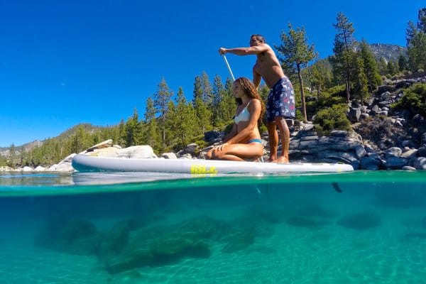 A couple paddle boarding on a lake.