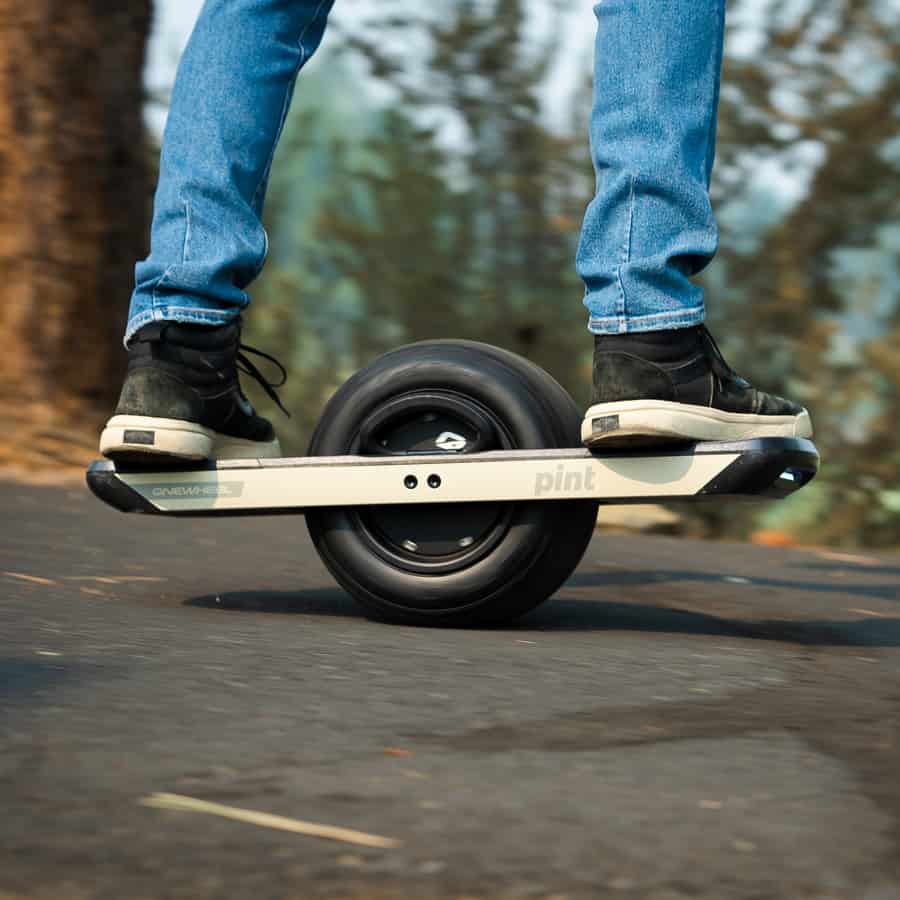 Man with blue jeans riding a Onewheel Pint.