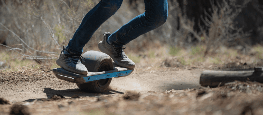 Image of man riding Pint X Onewheel through dirt fast